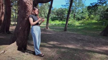 Ağacın yanında duran kadın güneşli havada eğleniyor.