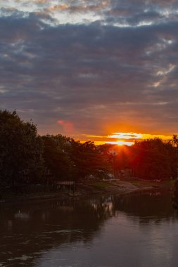 Sakin nehir suyunda yansıyan canlı günbatımı