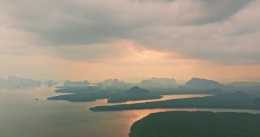Güneş ışığı bulutlu gökyüzünü saran nehrin üzerinde parlıyor.