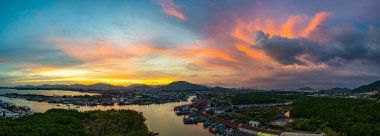Phuket 'teki balıkçı limanında sersemletici gün batımını gösteren hava manzarası. Yumuşak mor renkten ateşli turuncu renklere dönüşen canlı gökyüzü, sakin ve pitoresk bir atmosfer yaratır..  