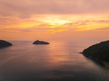 Güneşin Ao Mai Ngam, Surin Adaları 'ndan batışını gösteren hava manzarası. Batan güneşin yansıması. Bereketli yeşil tepeler ve demirlemiş yelkenlilerin silueti huzurlu ortamı geliştirirken.