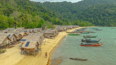 Morgan Köyü 'nün Surin Adası' ndaki doğal güzelliklere gizlenmiş havadan görüntüsü. Kıyı şeridi boyunca yemyeşil ormanlarla çevrili küçük kulübeler. Balıkçı tekneleri turkuaz sularda demirli..    