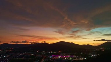 Kıyı kasabasının üstündeki gün batımında dramatik bulutların hava manzarası. Uzak bir tepe yapısı huzur dolu bir manzara ekliyor. Seyahat konseptinde hisse senedi. tatlı gökyüzü arkaplanı.