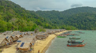 Morgan Köyü 'nün Surin Adası' ndaki doğal güzelliklere gizlenmiş havadan görüntüsü. Kıyı şeridi boyunca yemyeşil ormanlarla çevrili küçük kulübeler. Balıkçı tekneleri turkuaz sularda demirli..    