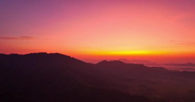 Sis uzak dağ sıralarına çökerken solgun bir gökyüzü altında şafağın yumuşak renklerini yansıtan sakin bir manzara. Güneşin doğuşunda inanılmaz pembe gökyüzü. renk renk gökyüzü dokusu