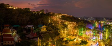 Havai fişeklerin göz kamaştırıcı gösterisi aydınlatılmış tepe sarayının üzerinde gece gökyüzünü aydınlatıyor. Bu coşkulu kutlama, karanlık gökyüzü ve Phetchaburi festivali havai fişekleriyle güzel bir tezat oluşturuyor..