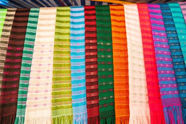 Karmaşık desenlere sahip kalın ve zengin renklerden oluşan geleneksel el dokuması kumaşların canlı bir gösterisi. Kuzeydeki dokuma geleneklerinin zanaatkarlığı ve kültürel mirası