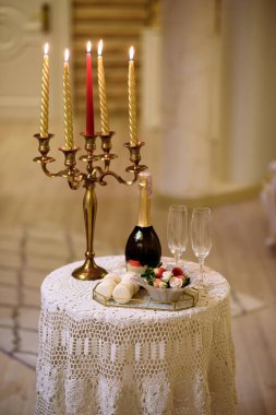 Mumlarla dolu eski bir şamdan ve masada gözlüklü bir şişe. 