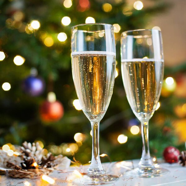 Два бокала шампанского в канун Нового года празднуют рождественские тосты в поддержку зимних праздников. Высокое качество фото