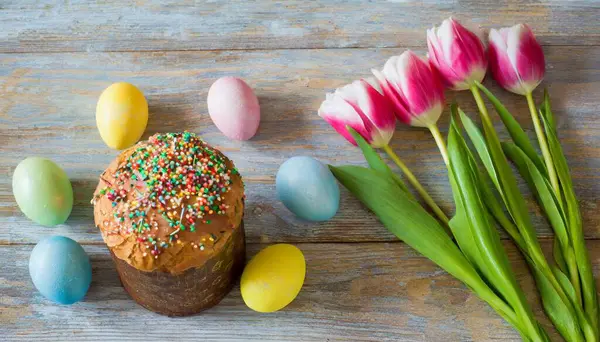 Paskalya yumurtası ve pasta gri masa arkasında. Bahar tatili için mutlu paskalya arkaplanı