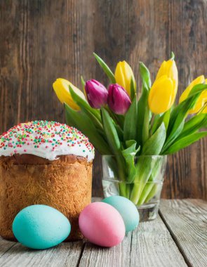 Paskalya yumurtası ve pasta gri masa arkasında. Bahar tatili için mutlu paskalya arkaplanı