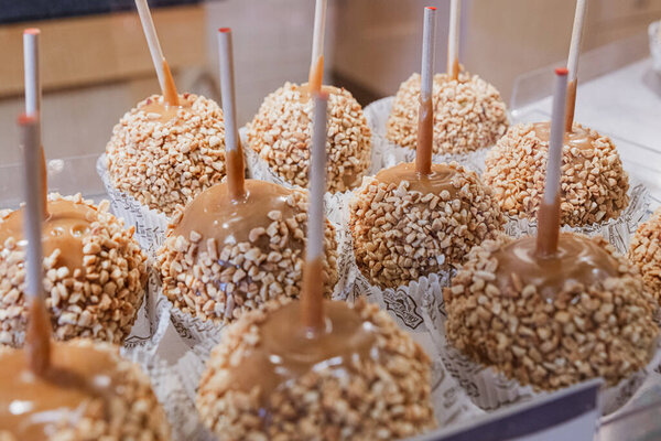 A tray of caramel apples sprinkled with nuts sit on display at a market in autumn.