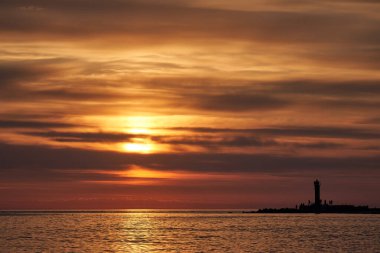 Akşam körfezi, deniz feneri ve gün batımı.