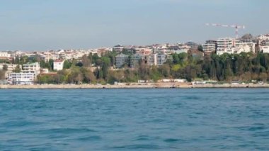 Bir gemi şehirden geçerken martılar uçar.