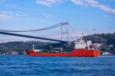 Boğaz 'daki Fatih Sultan Mehmet Köprüsü' nün altından geçen kırmızı bir tanker gemisi. Güzel İstanbul manzarası.