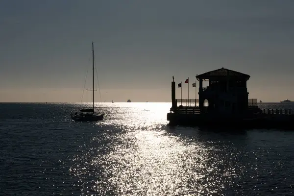 Denizin üzerinde gün batımı, feribot rıhtımına giden bir tekne..