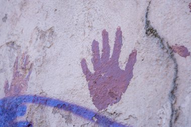 Grafiti kalıntıları olan bir şehir duvarında mor el izi.