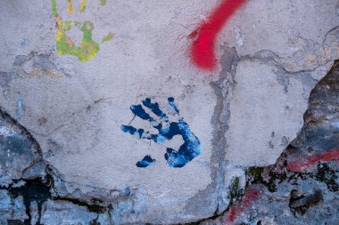 Çatlamış ve yıpranmış bir duvarda renkli el izleri