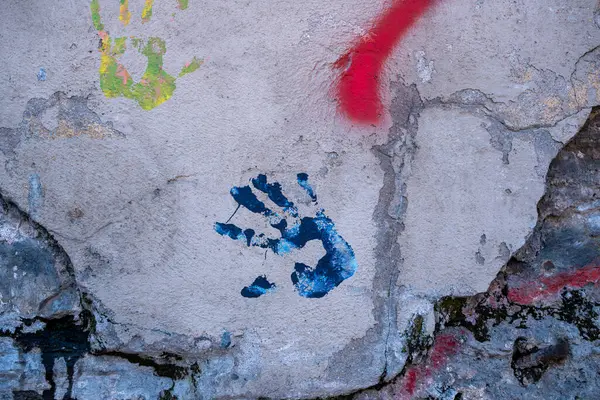 Çatlamış ve yıpranmış bir duvarda renkli el izleri