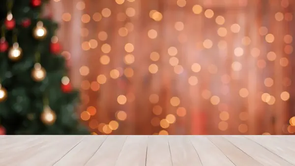 Background christmas scene with light wooden table for product image montage blurred background with christmas tree decorations and warm colored string lights