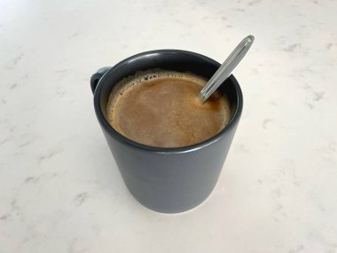 Beyaz mermer yüzeyinde kaşık olan kahve bardağının en iyi görüntüsü.