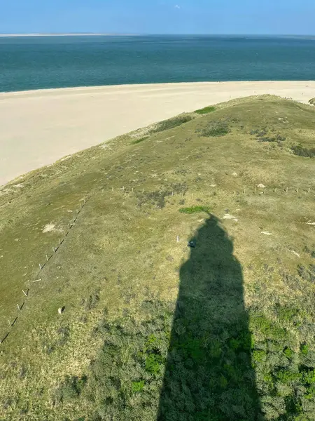 Teksaslı Deniz fenerinin uzun gölgesi Kum tepecikleri üzerinden Hollanda 'ya doğru uzanıyor.