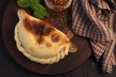 börek, hamur işi, ahşap tahta, çizgili kahverengi bez, calabrian biberi, baharat yaprakları, koyu ahşap masa