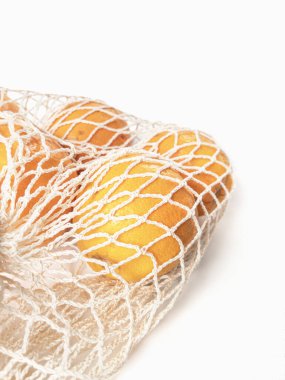 Yeniden kullanılabilir beyaz ağ torbasına taze soyulmamış portakallar yerleştirildi. Yüksek kalite fotoğraf