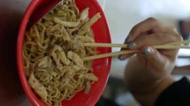 Tavuklu erişte, aylı fırında makarna. Kırmızı tabakta yemek çubuğu olan Endonezya Çin yemeği. dikey video