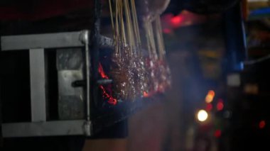 Yakın çekim, Sate ya da Satay 'ın dikey görüntüsü, Endonezya' dan gelen geleneksel yiyecekler yuvarlanıyor, kömürde kızartılıyor ve arkasından iğrenç bir hareket geliyor.