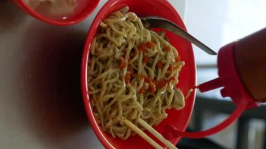 Bakmie Ayam 'a acı biber sosu, tavuk eriştesi ve yemek çubuğuyla karıştırmak, Endonezya Çin yemeği. mie ayam, dikey video