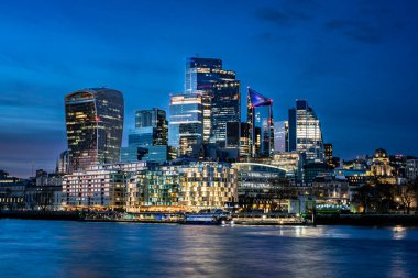 Günbatımında, modern gökdelenlerin alacakaranlık altında parlamaya başladığı Londra şehrinin panoramik görüntüsü. Finans, kentsel mimari, uluslararası iş ve Avrupa başkentlerinin gece manzaralarıyla ilgili projeler için mükemmel. Zarif. 