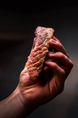 Pişmiş pirzola baharatlı ve şefin elinde. Ayrıntılı çekim.