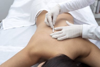 Estetik bir merkezde sedyede yatan genç bir kadın cilt bakımı ve neşterle cilt bakımı teknikleri ile yüz ve vücut güzelliği ve estetik tedavi uyguluyor.