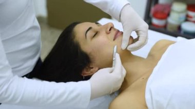 Bir estetik ve güzellik merkezinde bir güzellik uzmanı tarafından vücudun bakımı ve sağlığı için bir neşterle yapılan cilt bakımı tekniğiyle.