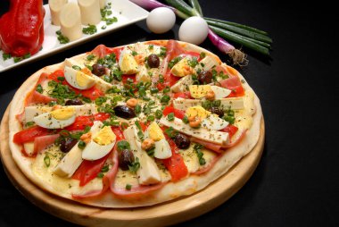 Sebze mantarlı çeşitli pizzalar farklı peynirler domates zeytinli roka kekikli biberli ahşap tahtada ve siyah masadaki malzemeler