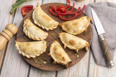 Ev yapımı börekler tavuk eti sebze, jambon ve peynirli ahşap tabakta sos ve limonla pişiriliyor. 