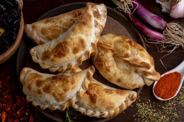 Ev yapımı börekler tavuk eti sebze, jambon ve peynirli ahşap tabakta sos ve limonla pişiriliyor. 