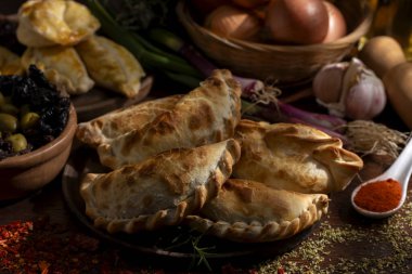 Ev yapımı börekler tavuk eti sebze, jambon ve peynirli ahşap tabakta sos ve limonla pişiriliyor. 