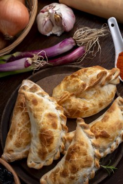 Ev yapımı börekler tavuk eti sebze, jambon ve peynirli ahşap tabakta sos ve limonla pişiriliyor. 