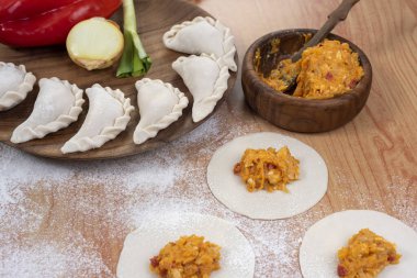 Hamurla çiğ ev yapımı börek yapma ve elleri birleştirme ve börekleri sebzelerle doldurma tavuk eti, jambon ve peynir ile doldurma ve repulgue yapma süreci. 