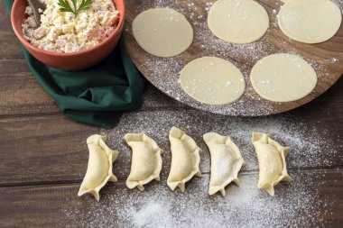 Hamurla çiğ ev yapımı börek yapma ve elleri birleştirme ve börekleri sebzelerle doldurma tavuk eti, jambon ve peynir ile doldurma ve repulgue yapma süreci. 