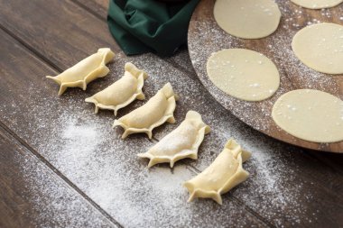 Hamurla çiğ ev yapımı börek yapma ve elleri birleştirme ve börekleri sebzelerle doldurma tavuk eti, jambon ve peynir ile doldurma ve repulgue yapma süreci. 