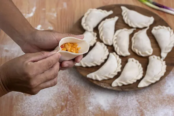 Hamurla çiğ ev yapımı börek yapma ve elleri birleştirme ve börekleri sebzelerle doldurma tavuk eti, jambon ve peynir ile doldurma ve repulgue yapma süreci. 