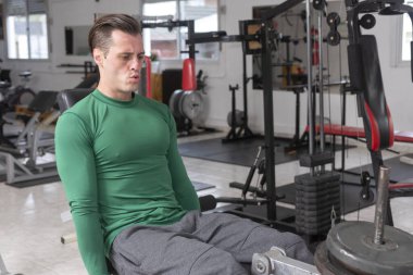 Spor salonunda halterli yetişkin bir adam sağlık ve zindelik eğitimi alıyor. 