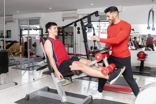 Spor salonunda ağırlıklar, halterler ve sağlık ve vücut bakımı için makinelerle beden eğitimi öğretmeni ve öğrenci. 
