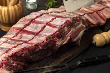 Sığır eti, pirzola ve ahşap tahta üzerinde biftek ve demir tabak baharatları ve malzemeler. 