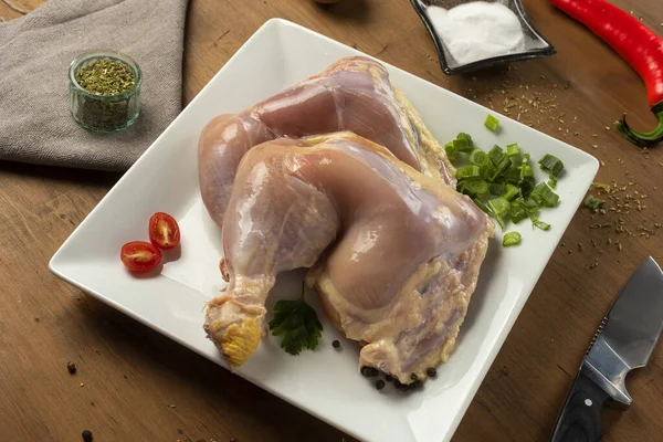 Whole fresh raw country chicken and leg and thigh on board and plate with ingredients and seasonings