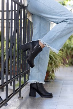 Farklı renklerde deri modellerden, kot, elbise ve taytlardan oluşan şık ayakkabıları olan kadın bacakları. 