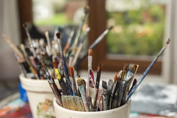 art and paint brushes inside a brush holder on the work table of an artistic painter